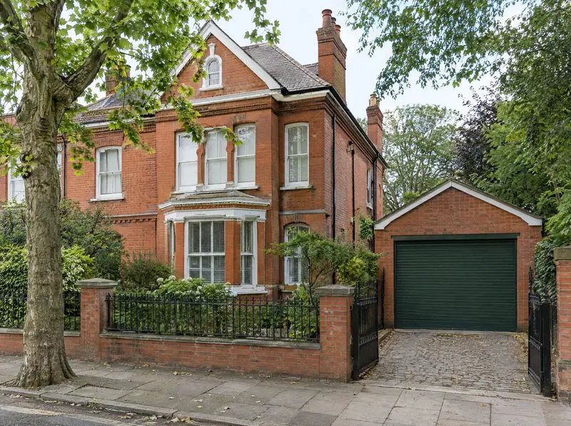 Edwardian red-brick house with a heritage green roller door on its detached garage