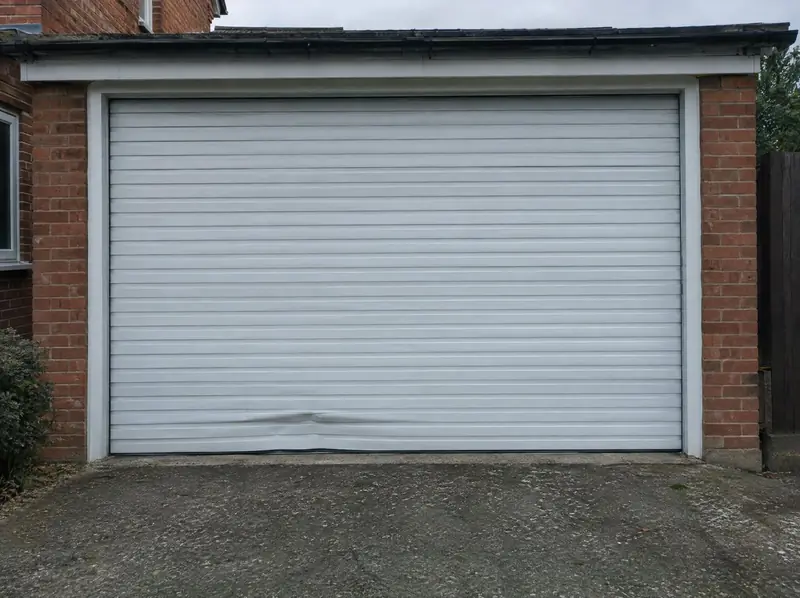 White roller garage door with one dented lath near the bottom