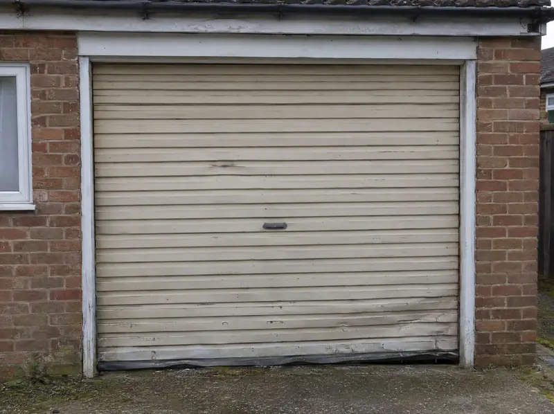 Old faded and dented beige roller garage door ready to be replaced