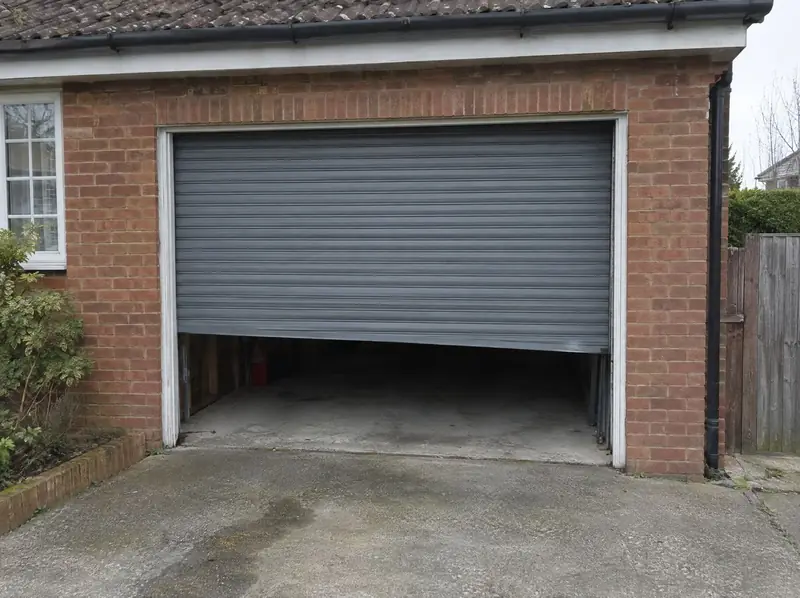 Grey roller garage door stuck part-open with one side lower than the other