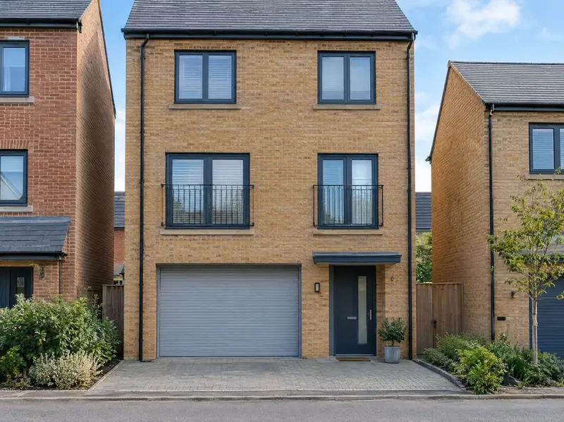 Three-storey townhouse with a grey roller door on its integral ground-floor garage